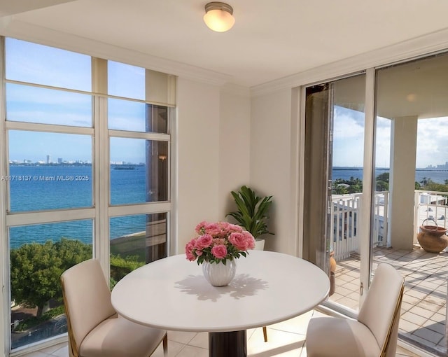 dining area featuring light tile patterned flooring, a water view, a wall of windows, and crown molding