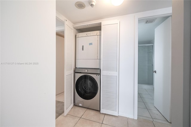 washroom featuring stacked washer / dryer and light tile patterned flooring