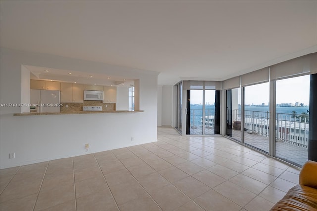 empty room featuring a water view and light tile patterned floors