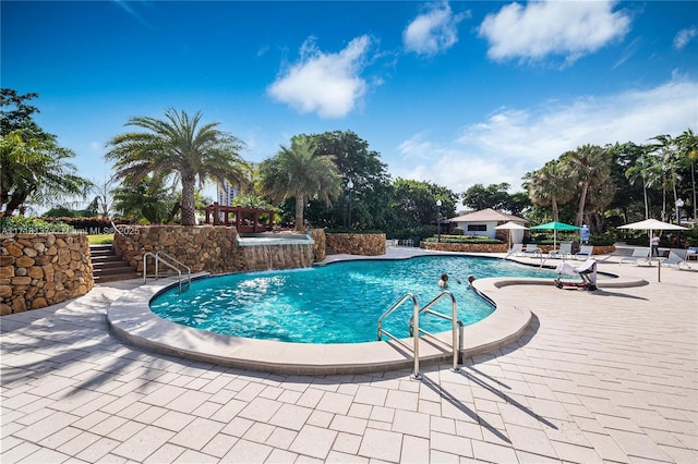 view of swimming pool with pool water feature and a patio