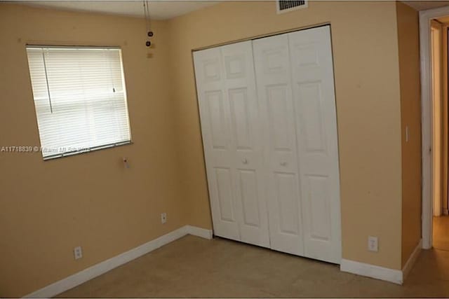 unfurnished bedroom featuring light colored carpet and a closet