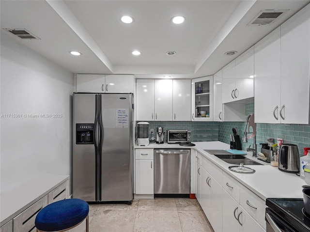 kitchen with backsplash, white cabinets, a raised ceiling, sink, and appliances with stainless steel finishes