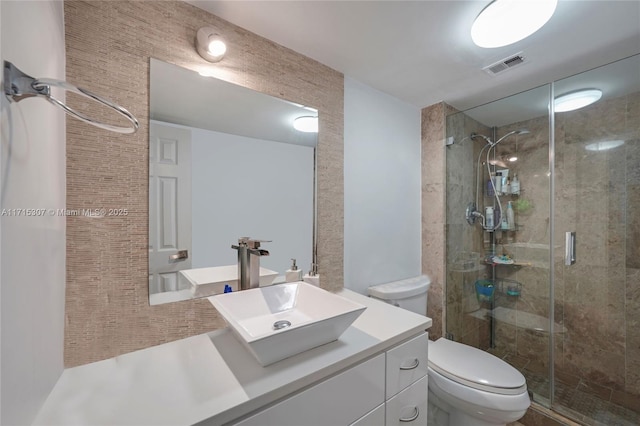 bathroom with visible vents, a shower stall, toilet, and vanity