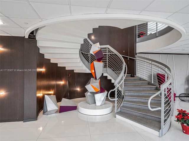 staircase featuring wooden walls and tile patterned floors