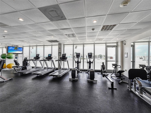 gym with a drop ceiling and a wall of windows