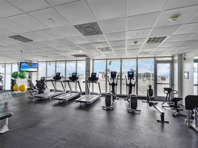 gym with a paneled ceiling, plenty of natural light, visible vents, and expansive windows
