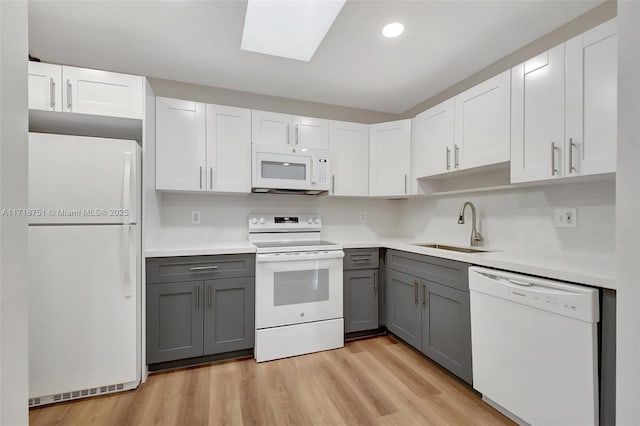 kitchen with white appliances, sink, gray cabinets, light hardwood / wood-style floors, and white cabinetry