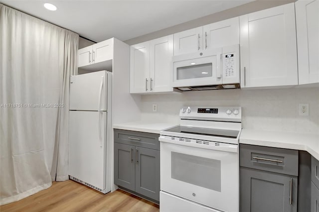 kitchen with white appliances, gray cabinets, white cabinetry, and light hardwood / wood-style floors