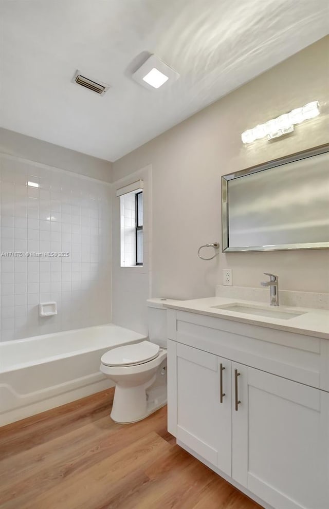 full bathroom with hardwood / wood-style floors, vanity, toilet, and tiled shower / bath