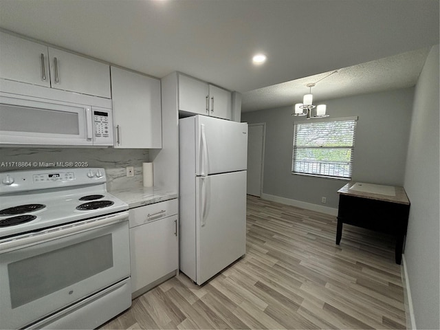 kitchen featuring backsplash, white appliances, pendant lighting, an inviting chandelier, and white cabinetry