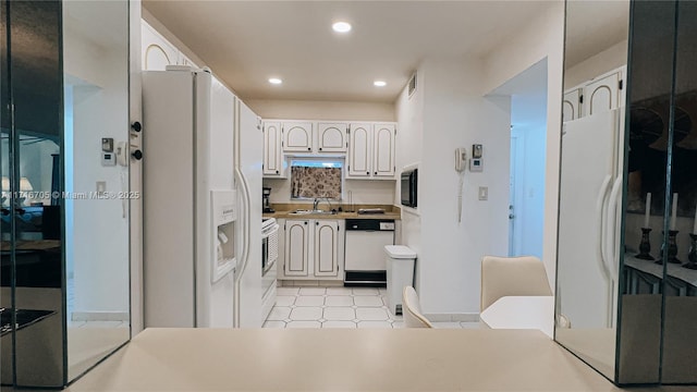 kitchen with white appliances, white cabinetry, and sink