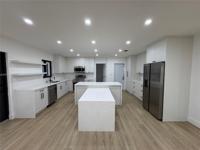 kitchen featuring a center island, white cabinets, sink, light wood-type flooring, and stainless steel appliances