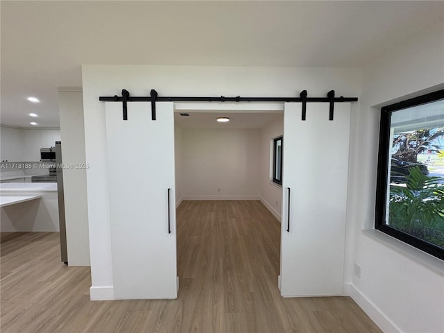 hallway with a barn door and light hardwood / wood-style flooring