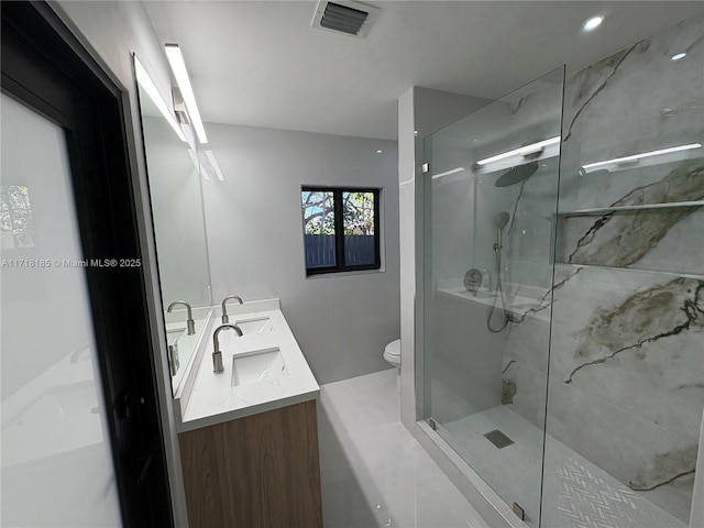 bathroom featuring a tile shower, vanity, and toilet