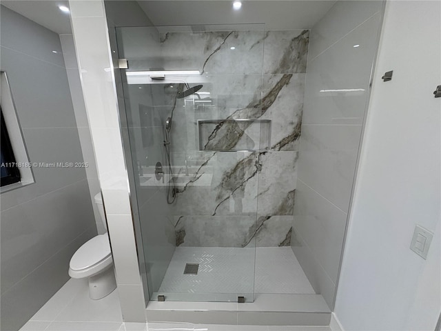 bathroom with a tile shower, tile patterned flooring, and toilet