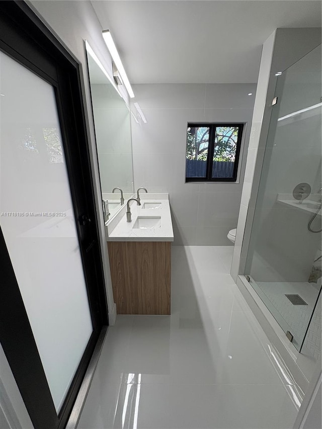 bathroom featuring walk in shower, tile patterned floors, toilet, vanity, and tile walls