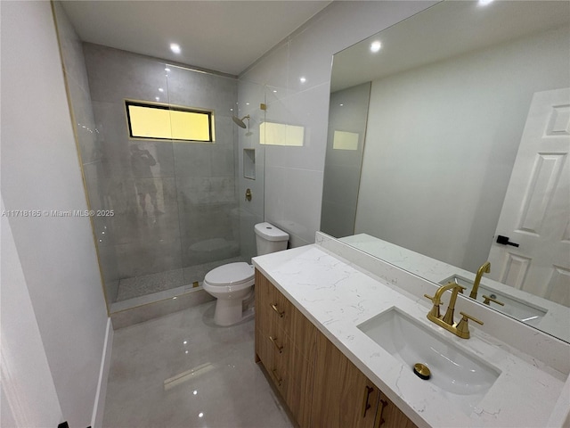 bathroom with a tile shower, vanity, and toilet