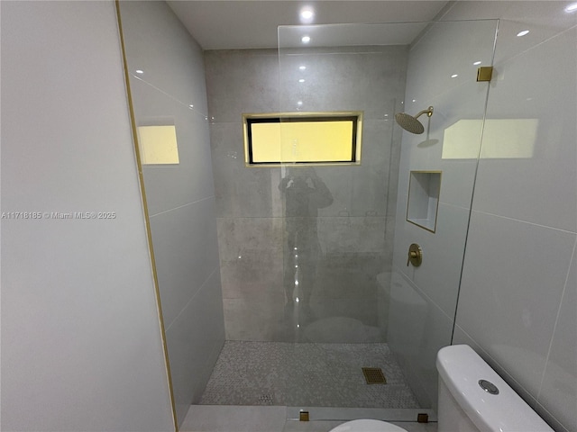 bathroom with toilet, tile walls, and tiled shower