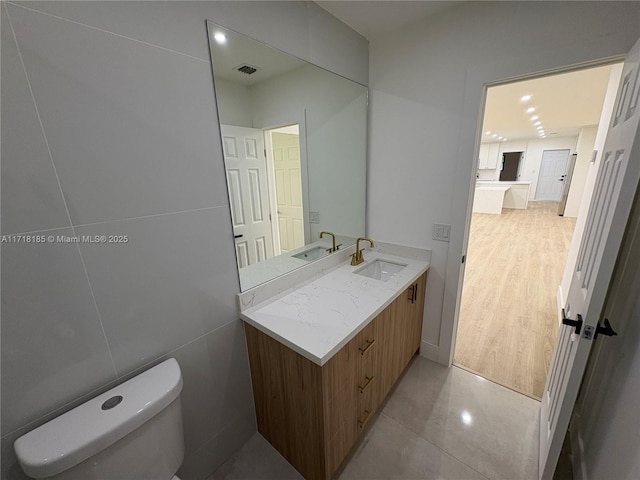 bathroom with tile patterned floors, vanity, toilet, and tile walls