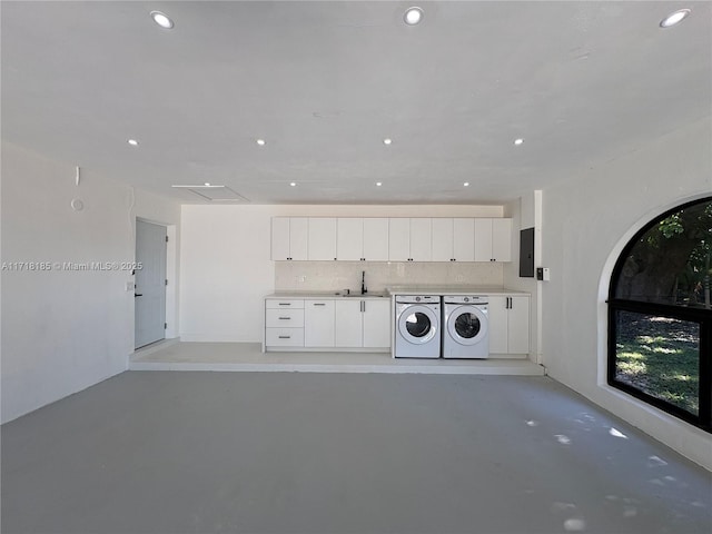 clothes washing area with separate washer and dryer, sink, and cabinets