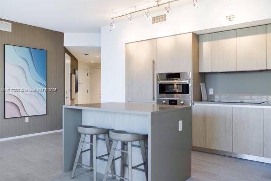 kitchen featuring a center island, stainless steel double oven, a kitchen bar, black electric cooktop, and wooden walls