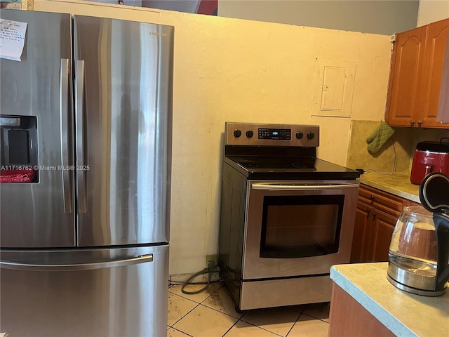 kitchen with electric panel, light tile patterned floors, and stainless steel appliances