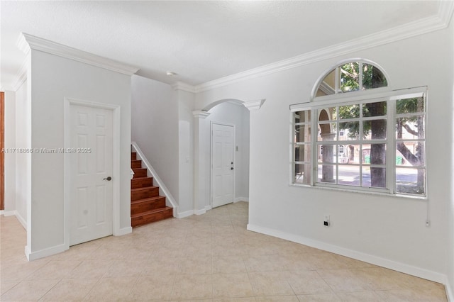 empty room with light tile patterned flooring, ornamental molding, and decorative columns