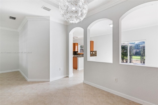 tiled empty room featuring an inviting chandelier and crown molding