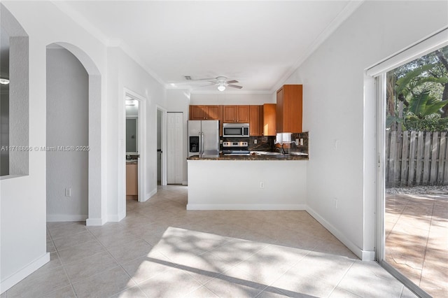 kitchen featuring kitchen peninsula, backsplash, stainless steel appliances, ceiling fan, and crown molding