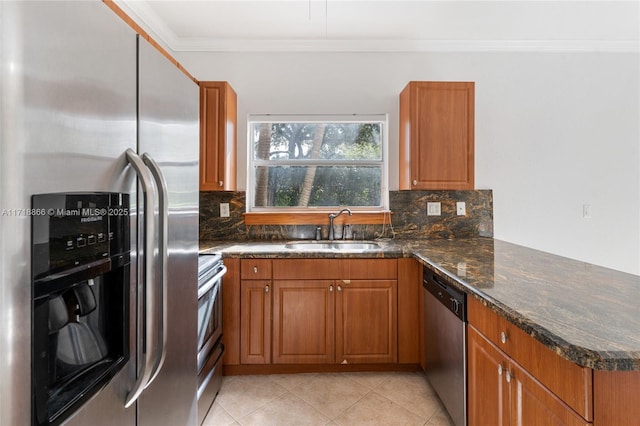 kitchen with sink, stainless steel appliances, dark stone countertops, light tile patterned floors, and ornamental molding