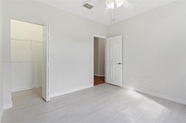 unfurnished bedroom featuring ceiling fan, a closet, a spacious closet, and light hardwood / wood-style flooring