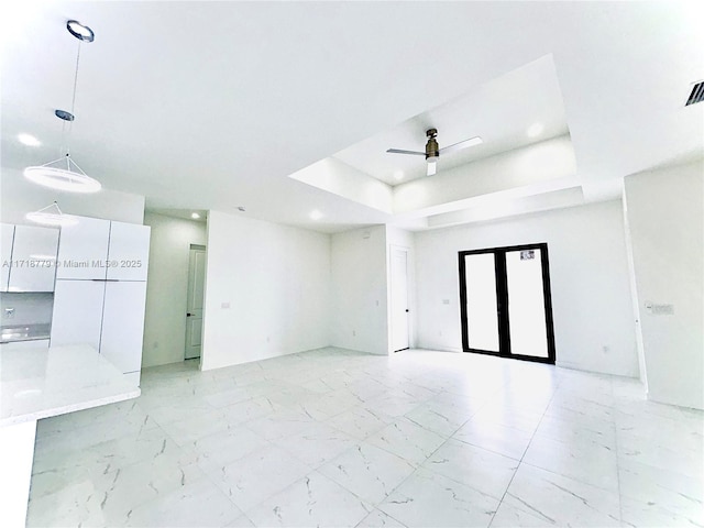 unfurnished room with ceiling fan and a tray ceiling