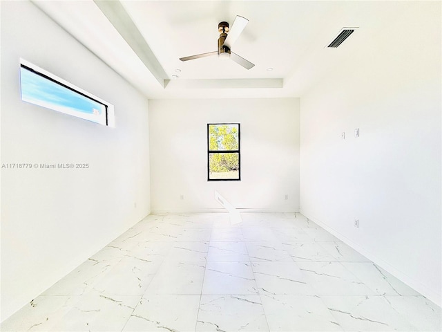 spare room with a tray ceiling and ceiling fan