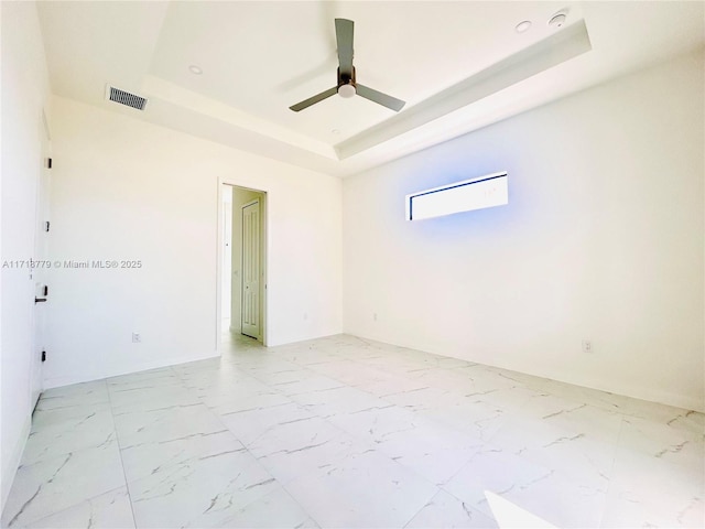 empty room featuring ceiling fan and a tray ceiling