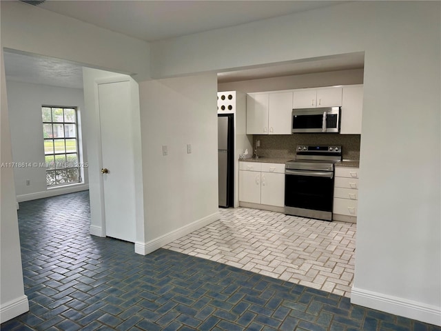 kitchen featuring white cabinets, decorative backsplash, and stainless steel appliances