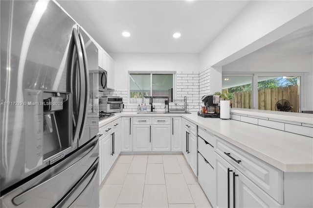 kitchen featuring kitchen peninsula, appliances with stainless steel finishes, tasteful backsplash, and white cabinetry