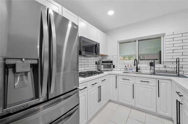 kitchen with white cabinets, backsplash, sink, and stainless steel appliances