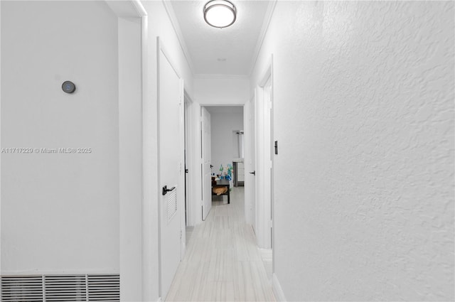 hallway with ornamental molding and a textured ceiling