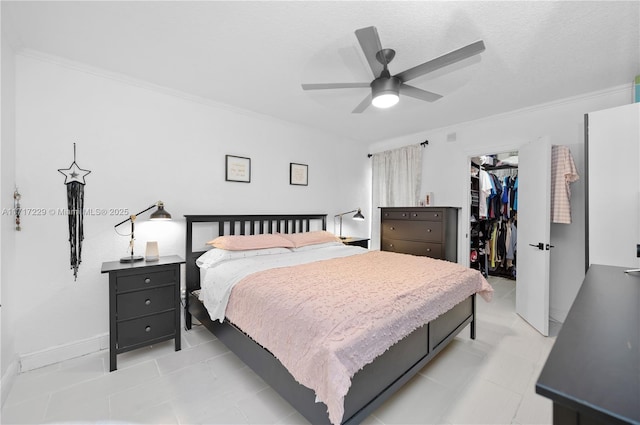 bedroom with a walk in closet, ornamental molding, a textured ceiling, ceiling fan, and a closet