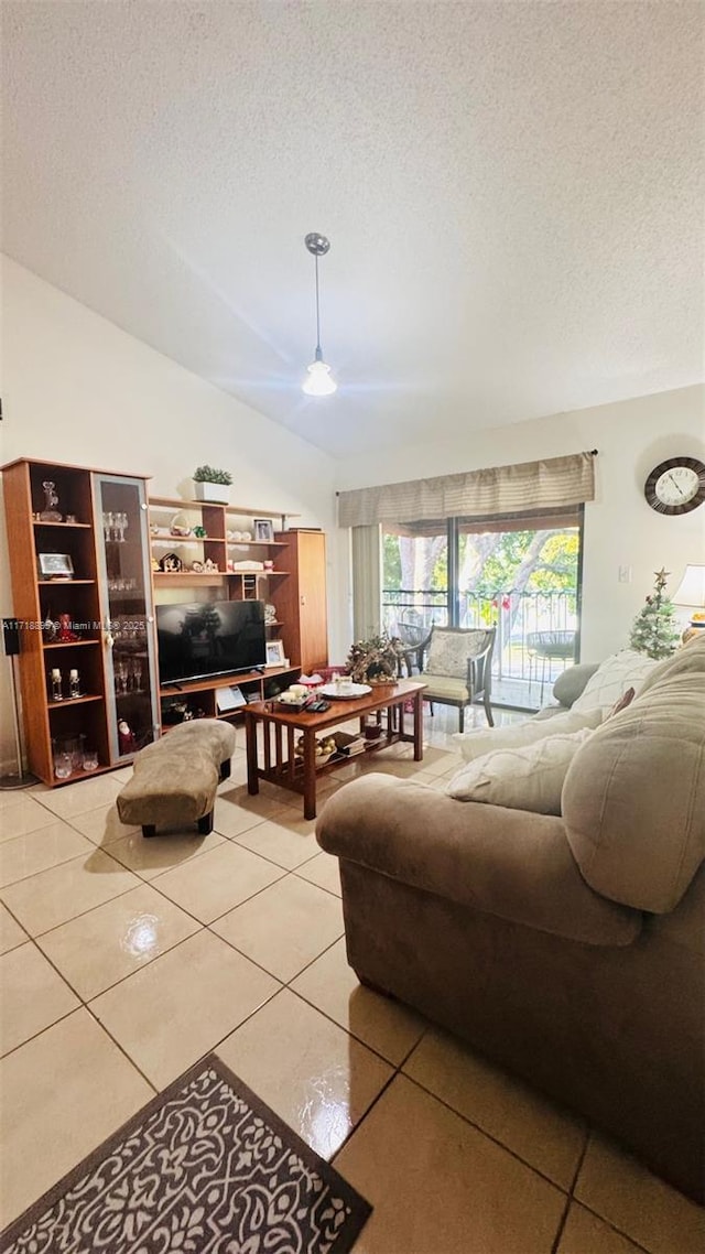 living room featuring a textured ceiling, vaulted ceiling, tile patterned floors, and ceiling fan