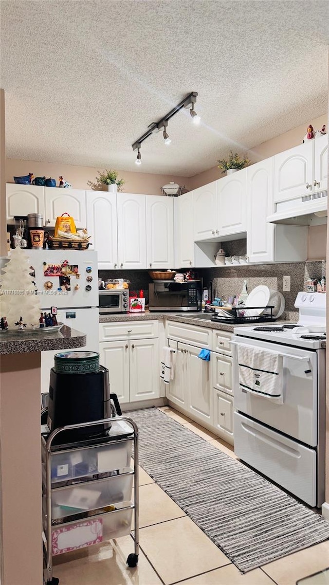 kitchen featuring white cabinetry, stainless steel appliances, a textured ceiling, decorative backsplash, and light tile patterned floors