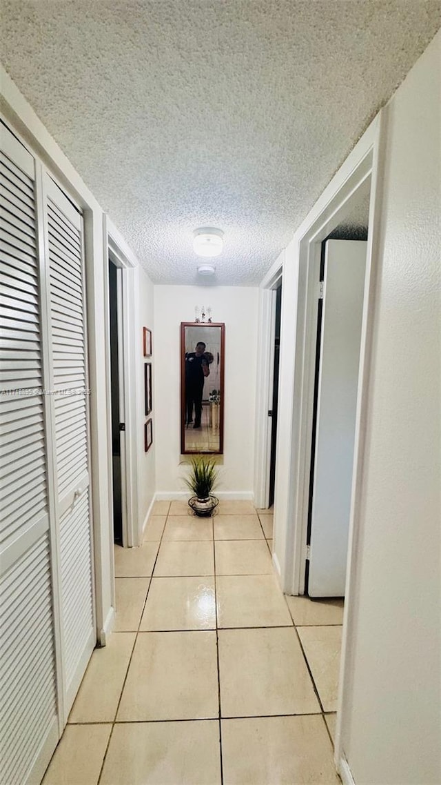 hall featuring light tile patterned floors and a textured ceiling