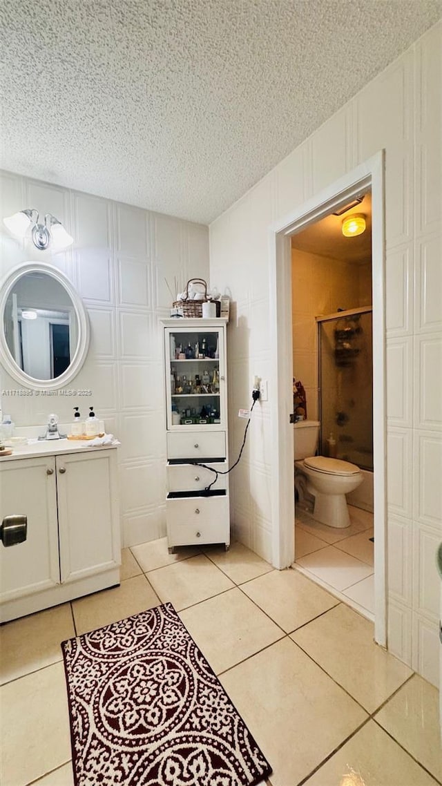 bathroom with tile patterned flooring, vanity, toilet, and walk in shower