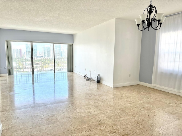 unfurnished room featuring baseboards, a chandelier, and a textured ceiling