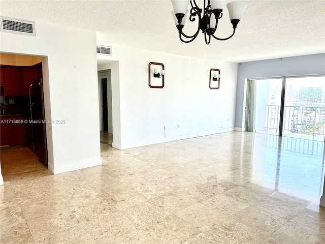 empty room featuring baseboards, visible vents, and a chandelier