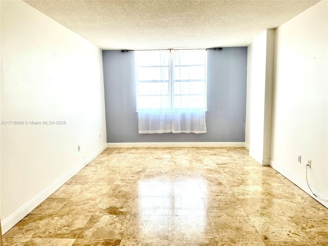 spare room with baseboards and a textured ceiling