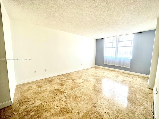 empty room with a textured ceiling and baseboards