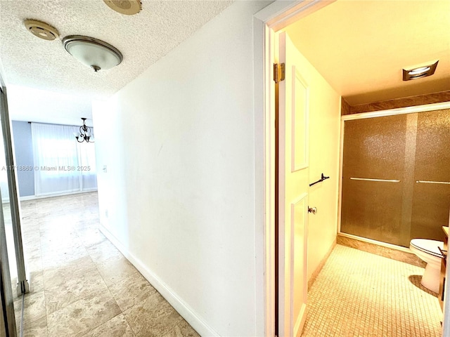 corridor featuring a textured ceiling and baseboards