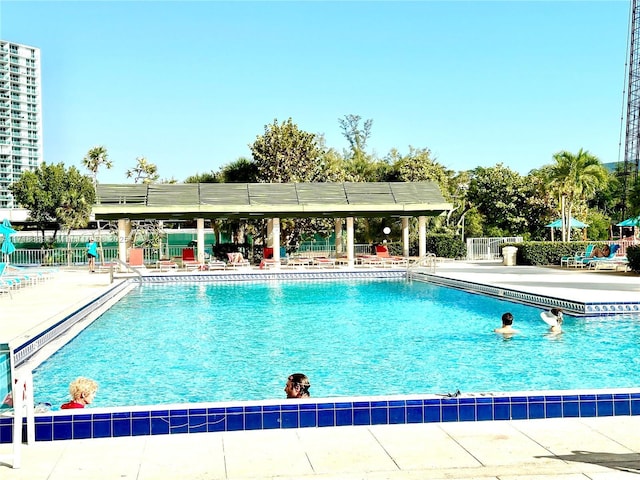 community pool with a patio area and fence