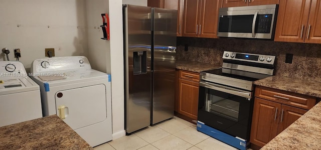 kitchen featuring washer and dryer, light tile patterned floors, appliances with stainless steel finishes, stone counters, and decorative backsplash